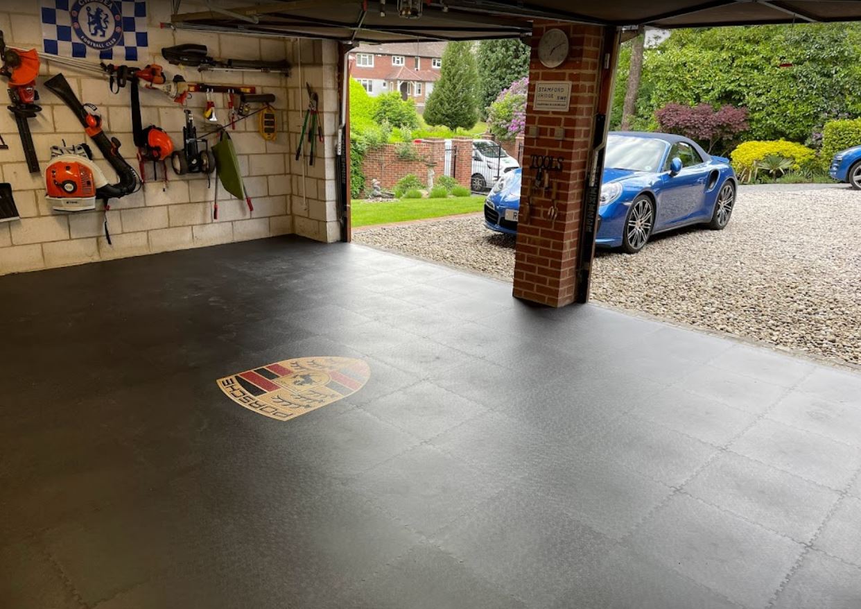 Graphite interlocking floor tiles in a residential garage with Porsche logo tile within the floor